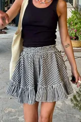 Falda corta con estampado de cuadros vichy en blanco y negro, tiro alto con elástico fruncido en la cintura y volado en el ruedo.