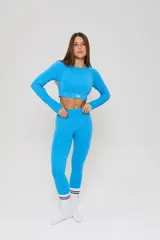 Conjunto deportivo compuesto por un top de bretel ancho con logo estampado y una calza chupín de tiro alto, ambos confeccionados en tejido seamless con textura.