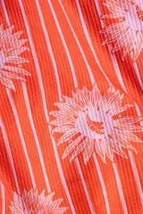 Traje de baño enterizo rojo con estampado de rayas verticales blancas y flores rosas. Tiene escote en V, breteles finos con apliques florales y copas con soporte.