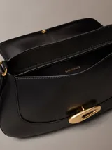 Cartera mediana con solapa Calvin Klein de color negro, confeccionada en poliuretano. Presenta diseño estructurado con cierre de broche a presión metálico dorado y correa ajustable.