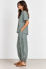 Pantalón de algodón a rayas verde oscuro y blanco, de corte holgado estilo globo con cintura elástica, bolsillos laterales y bajos ajustables con cordón.