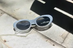Lentes de sol ovalados con marco de plástico color celeste y lentes oscuros con protección UV 400.