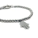 Pulsera de acero quirúrgico compuesta por pequeñas cuentas esféricas y un dije colgante en forma de mano de Fátima (Hamsa).