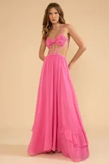 Vestido largo de chiffon color rosa, con busto estructurado y detalle de nudo en el centro, tirantes finos ajustables, aberturas laterales en la cintura y falda larga con vuelo y detalle de volados en el bajo.