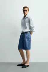 Bermuda de denim de algodón con corte relaxed fit, cintura con pliegues dobles en el delantero, bolsillos laterales y traseros de doble vivo, con efecto lavado y cierre frontal con cremallera y botón.