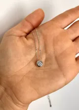 Collar plateado con dije circular con un cristal incrustado.