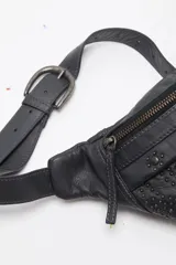 Riñonera de cuero negro con tachas aplicadas en el frente y cierre superior de cremallera.