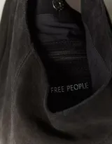 Bolso tipo hobo de gamuza color marrón, con silueta relajada y dos asas de hombro sujetas por argollas metálicas plateadas.