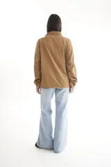 Camisa negra de pana, corte oversize, con cuello camisero, cierre frontal con botones, dos bolsillos con solapa en el pecho y mangas largas con puños abotonados.