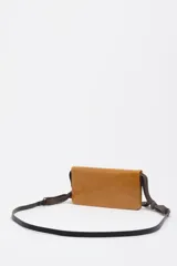 Bolso mini de piel vacuna color marrón, con diseño compacto y funcional. Presenta asa combinada de piel y cordón ajustable, logo metálico de la marca en el frente y cierre de cremallera.