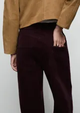 Jeans de tiro bajo y diseño wide leg, confeccionados en tejido de pana color bordó, con cierre de botón y cremallera, trabillas para cinturón y cinco bolsillos.