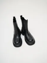 Bota tipo chelsea de cuero vacuno en color rojo con estampado floral grabado en negro. Presenta paneles laterales elásticos, suela de plataforma y taco cuadrado en color negro.