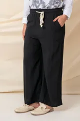 Pantalón ancho color beige, de hilo, con cintura elastizada ajustable con cordón y bolsillos laterales.