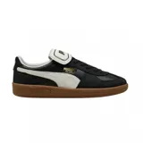Championes Puma modelo Palermo Premium, con diseño de perfil bajo en color negro con franja lateral blanca y suela de goma color caramelo.