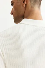 Remera polo de manga corta en punto trenzado suave, color blanco, con cuello abierto y remate acanalado en mangas y bajo.
