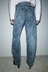 Jeans de tiro alto, estilo balloon leg, largo completo. Denim azul claro con efecto lavado ácido o 'acid wash'. Presenta cinco bolsillos y cierre frontal con cremallera y botón.