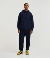 Pantalón jogger negro de algodón y poliéster, con cintura elástica y cordón ajustable. Presenta bolsillos laterales y puños ajustados en los tobillos.