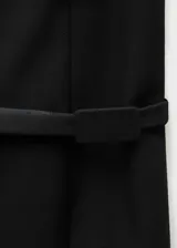 Minifalda negra de corte recto con diseño minimalista, que presenta un cinturón decorativo integrado en la cintura y una sutil abertura frontal.