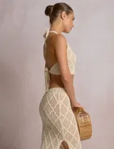 Top crop de tejido calado beige, con escote halter y patrón geométrico de rombos.