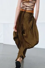 Pantalón de tiro medio confeccionado en viscosa, con diseño de pierna ancha y drapeado lateral. Presenta cintura con trabillas y cierre de cremallera oculto en la costura.