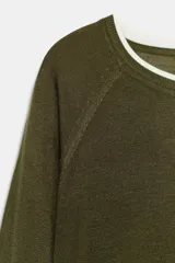 Jersey de punto verde militar con efecto doble, escote redondo y mangas largas con detalles en blanco en el cuello, puños y ruedo.