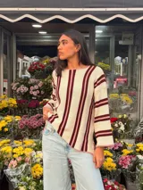 Sweater de tejido de punto de algodón con diseño rayado en color blanco, bordó y rosado, cuello redondo a la base, mangas largas acampanadas y silueta oversize.