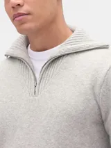 Buzo de punto con medio cierre frontal y cuello alto, confeccionado en tejido suave de textura jaspeada, con puños y ruedo acanalados.