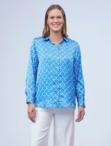Camisa de satén con estampado geométrico en azul y blanco, marca Hester & Orchard. Tiene cuello con solapa, escote en V y abertura frontal con botones.