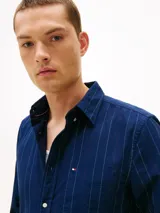Camisa azul oscuro de corte regular con patrón de raya diplomática blanca y roja, confeccionada en puro algodón Oxford. Cuenta con cuello abotonado, cierre frontal con botones, bolsillo de parche en el pecho con logo bordado y mangas largas con puños abotonados.