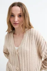 Cardigan beige de tejido calado con escote en V, manga larga y cierre frontal con tres botones.