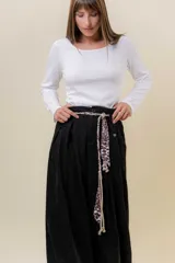Pantalón wide leg de tiro alto en color negro, con diseño de pinzas delanteras que aportan volumen y caída fluida. Incluye bolsillos laterales y un lazo desmontable en la cintura que combina cordón con cinta de estampado animal print.