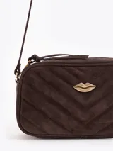 Bandolera de cuero gamuzado color marrón, con diseño matelaseado en chevron, correa larga ajustable y detalle metálico dorado con forma de labios en el frente.