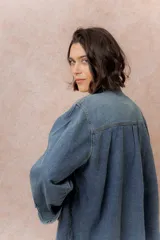 Camisa de denim de lavado medio con calce oversize, cuello camisero, cierre frontal con botones y bolsillos aplicados en el frente.