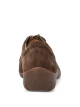 Zapato casual de mujer Hush Puppies modelo Rojam, confeccionado en cuero gamuzado color marrón. Presenta cierre mediante cordones al tono, suela de goma flexible y detalle de logo metálico en el lateral.