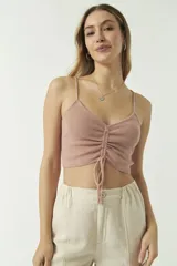 Top de punto color menta con escote en V, tirantes finos y detalle de fruncido central ajustable con cordón. Presenta un diseño corto y entallado.