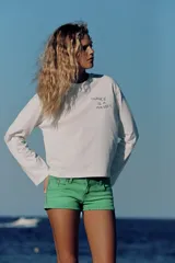 Remera blanca de manga larga y cuello redondo con detalle de texto impreso en el pecho en color azul.