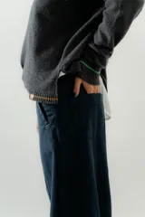 Pantalón de tiro medio-alto con piernas anchas y corte recto. Presenta cierre frontal con botón, bolsillos laterales y detalles de costuras verticales. Confeccionado en tencel.