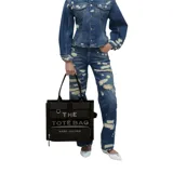Bolso tipo tote grande de Marc Jacobs, confeccionado en lona de algodón color negro. Presenta diseño utilitario con múltiples bolsillos frontales con solapa, un bolsillo con cierre y el texto "THE TOTE BAG" impreso en contraste. Cuenta con asas superiores dobles.