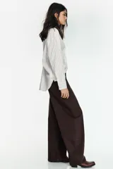 Camisa de corte oversize con estampado de rayas verticales, cuello solapa, cierre frontal con botones y mangas largas con puños abotonados.