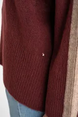 Polera de punto con calce oversize, cuello alto y mangas largas. Presenta un diseño en color negro con franjas laterales en las mangas y detalle en el cuello en tono bronce con acabado brillante.