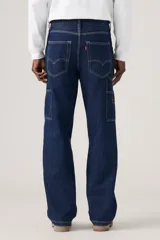 Jeans de denim azul oscuro con corte holgado y recto, estilo carpintero, con trabillas para cinturón y bolsillos funcionales.