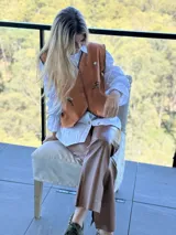 Chaleco color tostado con bordados florales artesanales, cierre frontal con botones y costuras decorativas en contraste en los bordes.