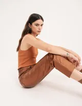 Pantalón negro estilo jeanero confeccionado en gabardina elastizada con terminación metalizada, pierna recta con largo por arriba del tobillo, cierre delantero y botón.