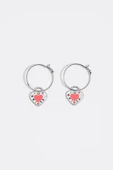 Aros de metal tipo argolla con dije colgante en forma de corazón esmaltado en color blanco y rosado, con detalles de letras estampadas.