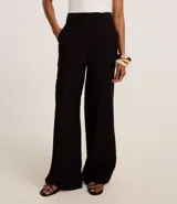 Pantalón de vestir azul marino, de corte amplio, con cintura alta, cinturón incorporado y cierre delantero.