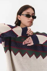 Buzo de tejido de punto con diseño geométrico y combinación de colores en contraste. Presenta cuello redondo, mangas largas y corte oversized.
