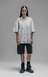 Camisa de manga corta y corte holgado con diseño de bordado broderie en toda la prenda, cuello camisero y cierre frontal de botones.