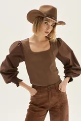 Pantalón wide leg de cuero sintético color marrón, con tajo frontal en el ruedo y cierre de botón y cremallera.