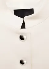 Chaqueta corta de diseño recto con cuello mao y cierre frontal de botones con efecto joya. Posee mangas largas y forro interior.