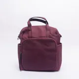 Mochila de cuero sintético color bordó, con textura granulada y bolsillo frontal liso con cierre. Posee manijas superiores y compartimentos laterales.